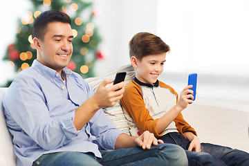 Image showing happy father and son with smartphones at christmas