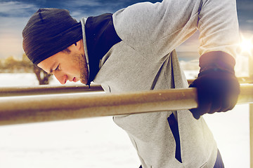 Image showing young man exercising on parallel bars in winter