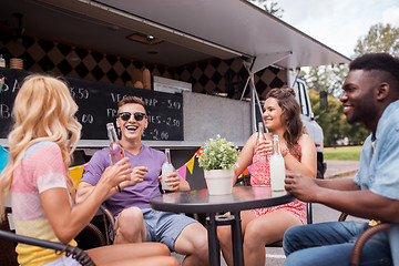 Image showing friends with drinks sitting at table at food truck