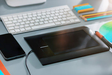 Image showing The gray desk with laptop, notepad with blank sheet, pot of flower, stylus and tablet for retouching