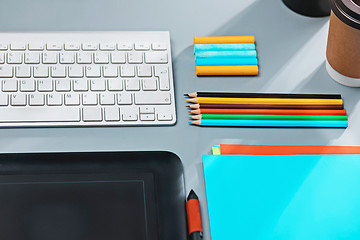 Image showing The gray desk with laptop, notepad with blank sheet, pot of flower, stylus and tablet for retouching