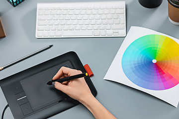 Image showing The gray desk with laptop, notepad with blank sheet, pot of flower, stylus and tablet for retouching