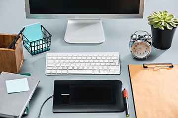 Image showing The gray desk with laptop, notepad with blank sheet, pot of flower, stylus and tablet for retouching