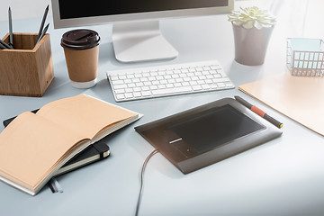 Image showing The gray desk with laptop, notepad with blank sheet, pot of flower, stylus and tablet for retouching