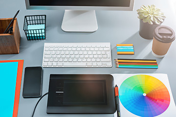 Image showing The gray desk with laptop, notepad with blank sheet, pot of flower, stylus and tablet for retouching