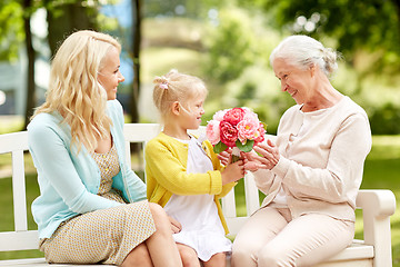 Image showing happy family giving flowers to grandmother at park