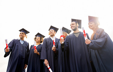 Image showing happy students in mortar boards with diplomas