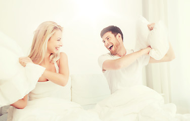 Image showing happy couple having pillow fight in bed at home