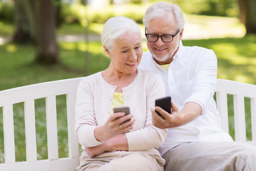 Image showing happy senior couple with smartphones at park