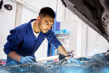 Image showing mechanic man with lamp repairing car at workshop