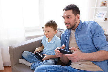 Image showing father and son playing video game at home