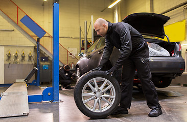 Image showing auto mechanic changing car tire at workshop