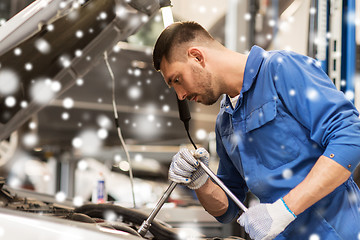 Image showing mechanic man with wrench repairing car at workshop