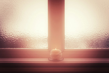 Image showing Frosted window and burning candle and in misty light