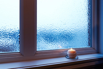 Image showing Cozy candle burning near a frosted window