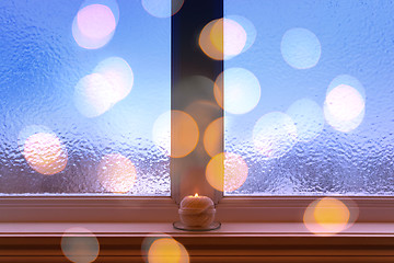 Image showing Frosted window, burning candle and bokeh lights