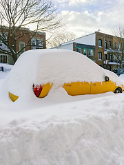 Image showing Urban street with a yellow car stuck in snow