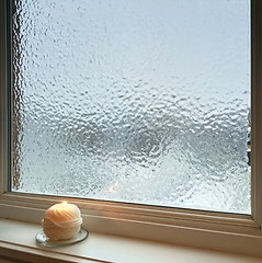 Image showing Candle burning near frosted window