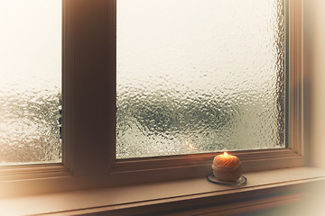 Image showing Burning candle and frosted window in hazy light