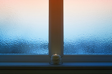 Image showing Frosted evening window with a candle burning