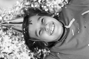 Image showing kid blowing confetti while lying on the floor