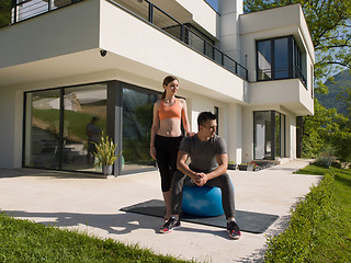 Image showing woman and personal trainer doing exercise with pilates ball