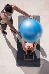 Image showing woman and personal trainer doing exercise with pilates ball