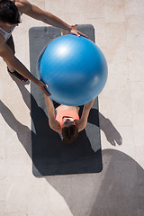 Image showing woman and personal trainer doing exercise with pilates ball