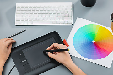 Image showing The gray desk with laptop, notepad with blank sheet, pot of flower, stylus and tablet for retouching