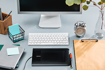 Image showing The gray desk with laptop, notepad with blank sheet, pot of flower, stylus and tablet for retouching