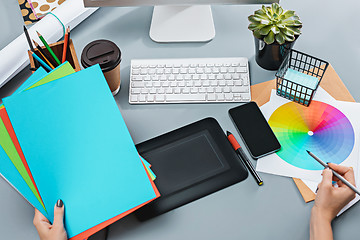 Image showing The gray desk with laptop, notepad with blank sheet, pot of flower, stylus and tablet for retouching