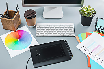 Image showing The gray desk with laptop, notepad with blank sheet, pot of flower, stylus and tablet for retouching