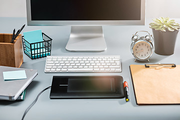 Image showing The gray desk with laptop, notepad with blank sheet, pot of flower, stylus and tablet for retouching