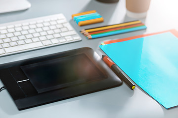 Image showing The gray desk with laptop, notepad with blank sheet, pot of flower, stylus and tablet for retouching