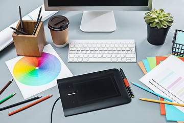 Image showing The gray desk with laptop, notepad with blank sheet, pot of flower, stylus and tablet for retouching