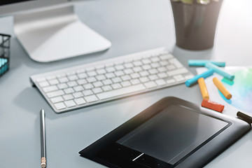 Image showing The gray desk with laptop, notepad with blank sheet, pot of flower, stylus and tablet for retouching