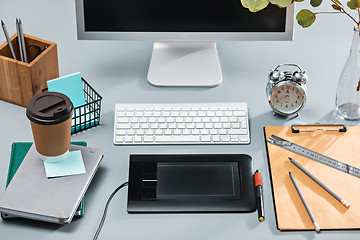 Image showing The gray desk with laptop, notepad with blank sheet, pot of flower, stylus and tablet for retouching