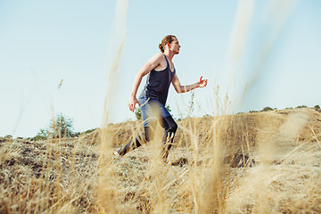 Image showing Running sport. Man runner sprinting outdoor in scenic nature. Fit muscular male athlete training trail running for marathon run.