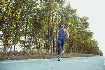 Image showing Running sport. Man runner sprinting outdoor in scenic nature. Fit muscular male athlete training trail running for marathon run.