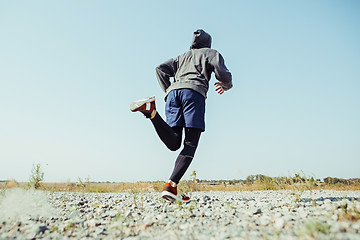 Image showing Running sport. Man runner sprinting outdoor in scenic nature. Fit muscular male athlete training trail running for marathon run.