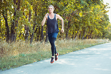 Image showing Running sport. Man runner sprinting outdoor in scenic nature. Fit muscular male athlete training trail running for marathon run.