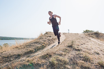 Image showing Running sport. Man runner sprinting outdoor in scenic nature. Fit muscular male athlete training trail running for marathon run.