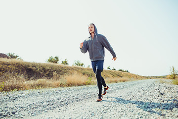 Image showing Running sport. Man runner sprinting outdoor in scenic nature. Fit muscular male athlete training trail running for marathon run.