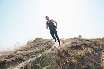 Image showing Running sport. Man runner sprinting outdoor in scenic nature. Fit muscular male athlete training trail running for marathon run.