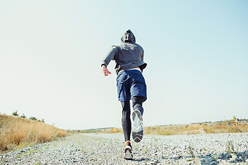 Image showing Running sport. Man runner sprinting outdoor in scenic nature. Fit muscular male athlete training trail running for marathon run.