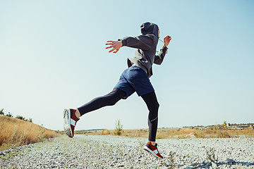 Image showing Running sport. Man runner sprinting outdoor in scenic nature. Fit muscular male athlete training trail running for marathon run.