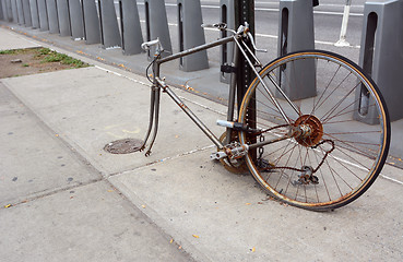 Image showing Broken, rusty bicycle locked to a metal pole