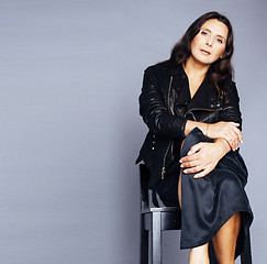 Image showing pretty brunette confident mature woman sitting on chair in studio, lifestyle people concept closeup