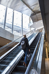 Image showing Businesswoman with large black bag and mobile phone ascending on escalator.