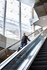 Image showing Businesswoman with large black bag and mobile phone descending on escalator.